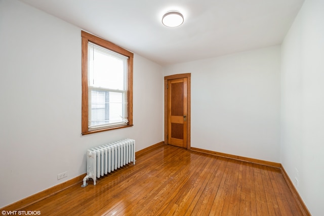 empty room featuring radiator heating unit and light wood-type flooring