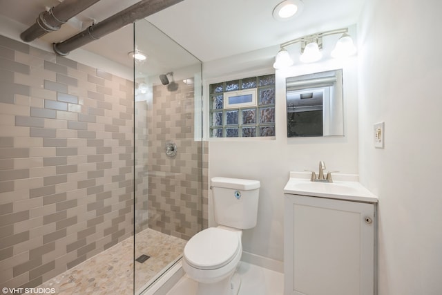 bathroom with vanity, tiled shower, and toilet