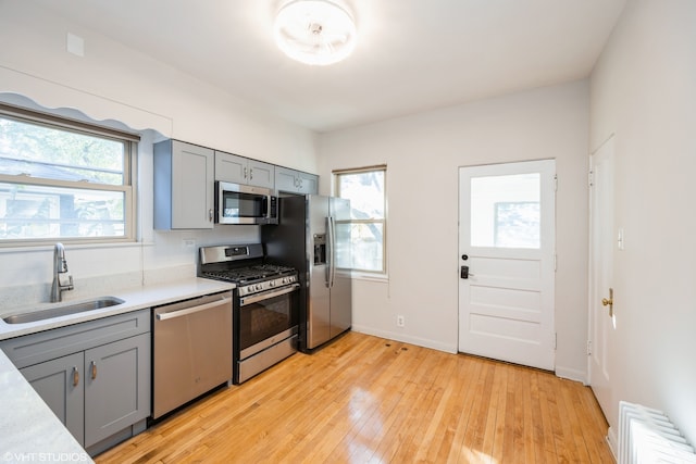 kitchen with light hardwood / wood-style flooring, appliances with stainless steel finishes, sink, and a wealth of natural light