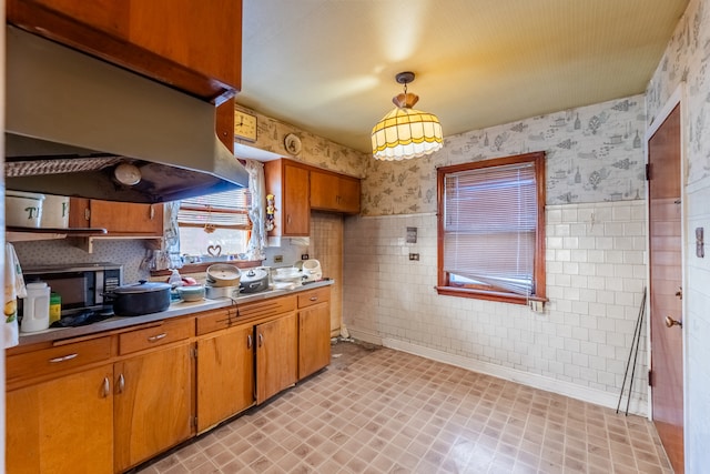 kitchen featuring tile walls, exhaust hood, and decorative light fixtures