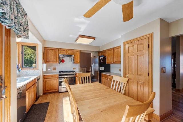 kitchen with decorative backsplash, appliances with stainless steel finishes, ceiling fan, sink, and light hardwood / wood-style floors