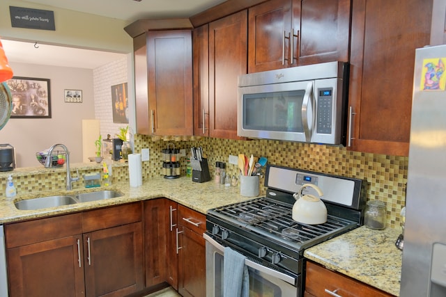 kitchen featuring light stone countertops, stainless steel appliances, sink, and tasteful backsplash