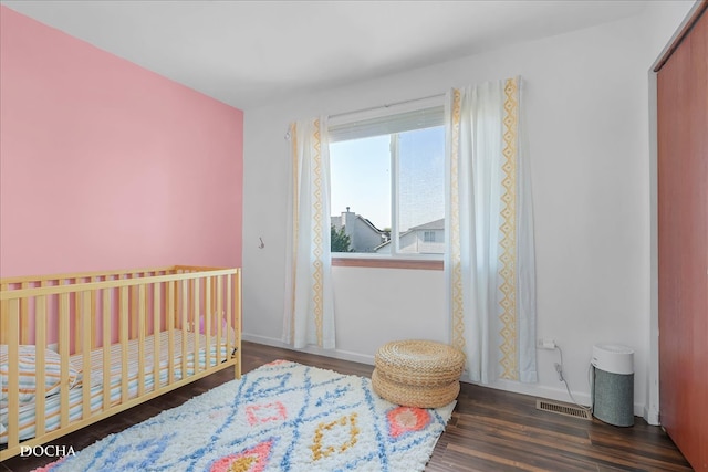 bedroom with dark wood-type flooring and a nursery area