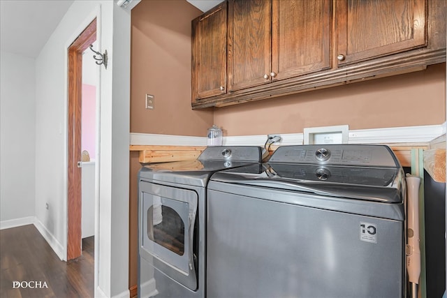 clothes washing area featuring independent washer and dryer, dark wood-type flooring, and cabinets