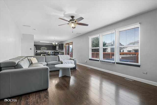 living room with ceiling fan with notable chandelier and dark wood-type flooring