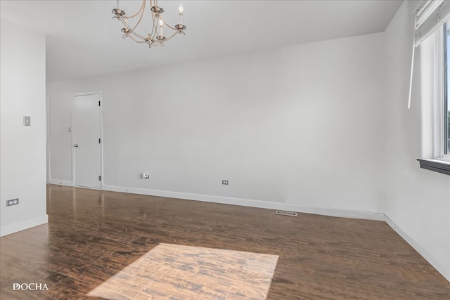 unfurnished room with dark wood-type flooring and an inviting chandelier