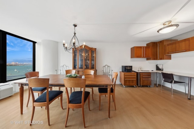 dining room featuring a water view, an inviting chandelier, and light hardwood / wood-style floors