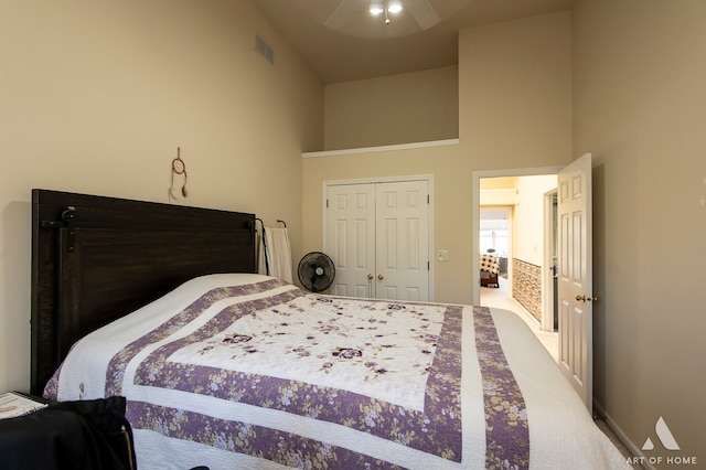 carpeted bedroom with a closet, ceiling fan, and a high ceiling