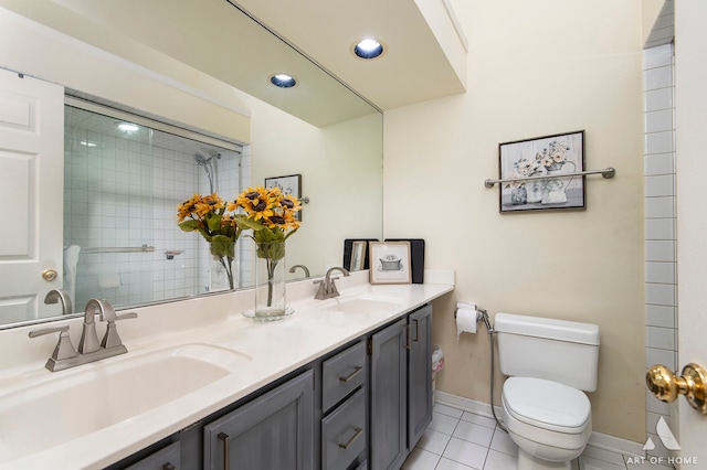 bathroom with tiled shower, tile patterned flooring, vanity, and toilet