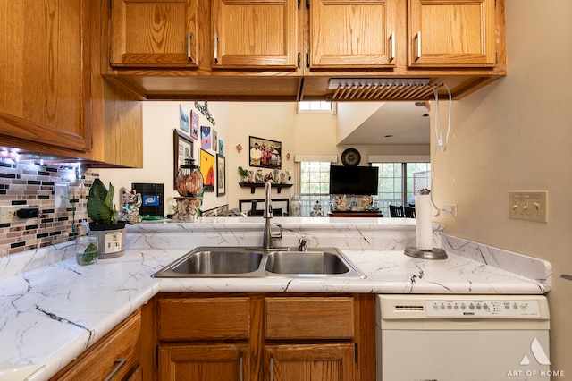 kitchen featuring backsplash, sink, and white dishwasher