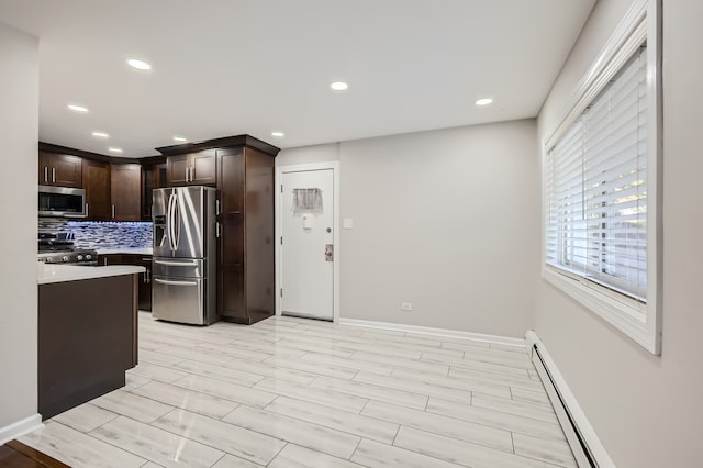 kitchen with appliances with stainless steel finishes, light wood-type flooring, dark brown cabinets, and tasteful backsplash