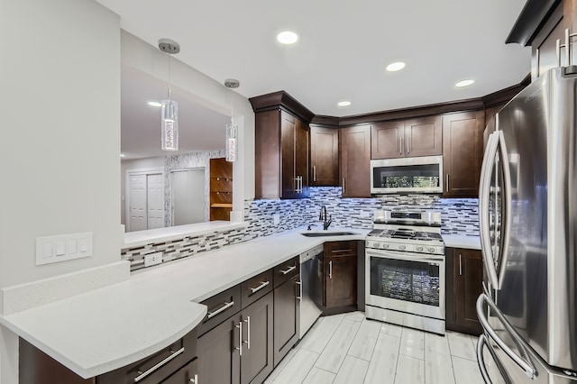 kitchen with appliances with stainless steel finishes, backsplash, kitchen peninsula, decorative light fixtures, and sink