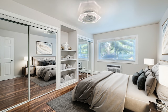 bedroom with an AC wall unit, dark hardwood / wood-style flooring, a baseboard heating unit, and a closet