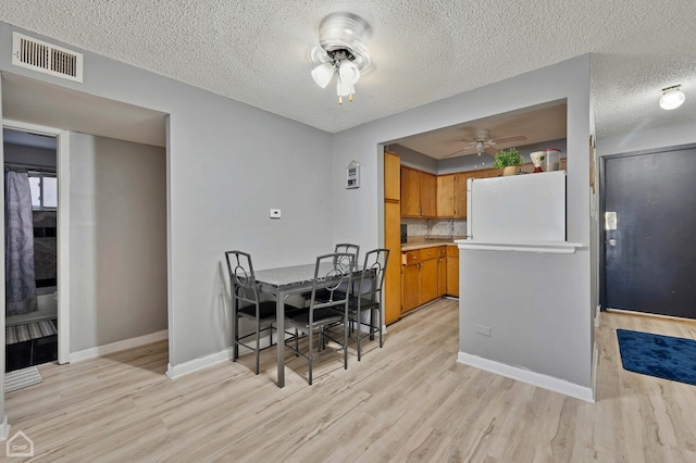 dining room with a textured ceiling, ceiling fan, and light hardwood / wood-style flooring