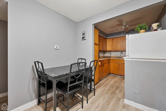 dining room featuring light hardwood / wood-style floors, ceiling fan, sink, and a textured ceiling