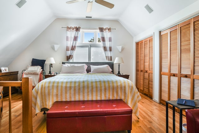 bedroom featuring two closets, lofted ceiling, ceiling fan, and hardwood / wood-style floors