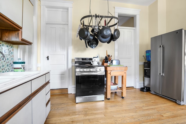 kitchen featuring light hardwood / wood-style floors, white cabinetry, stainless steel appliances, and a notable chandelier