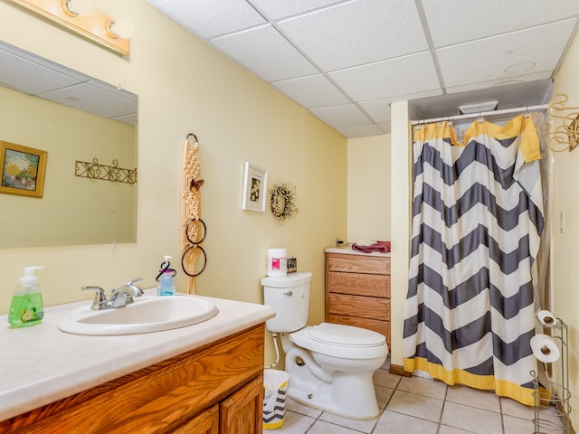 bathroom with toilet, a drop ceiling, tile patterned floors, vanity, and curtained shower