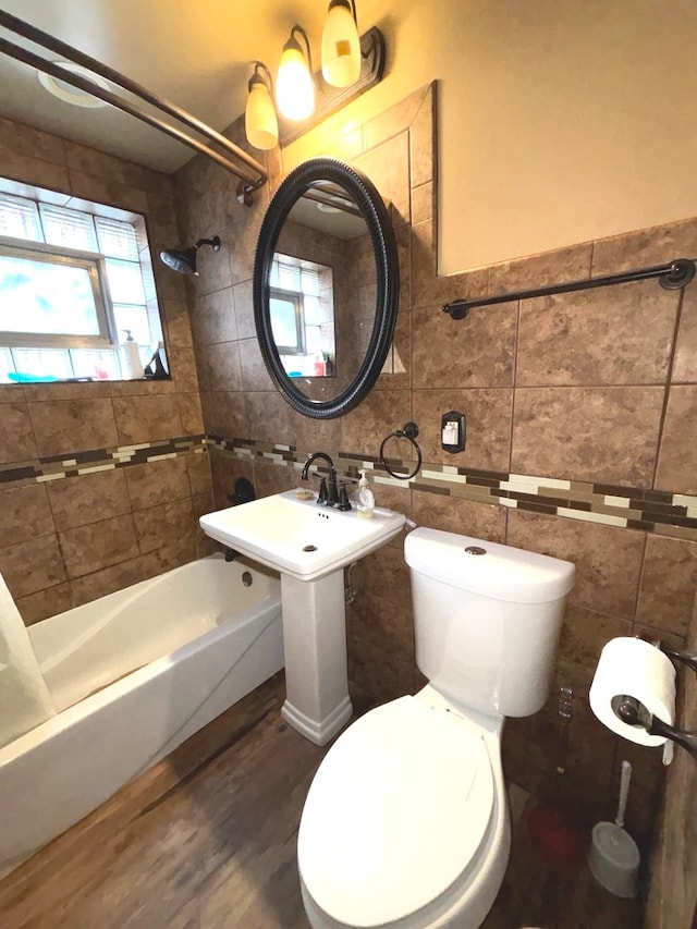 bathroom with hardwood / wood-style flooring, tile walls, toilet, and shower / bath combination with curtain