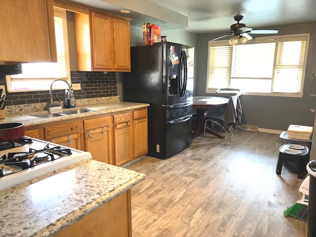 kitchen featuring sink, light hardwood / wood-style flooring, decorative backsplash, ceiling fan, and black refrigerator with ice dispenser