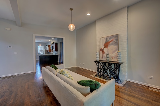 living room featuring beamed ceiling and dark wood-type flooring