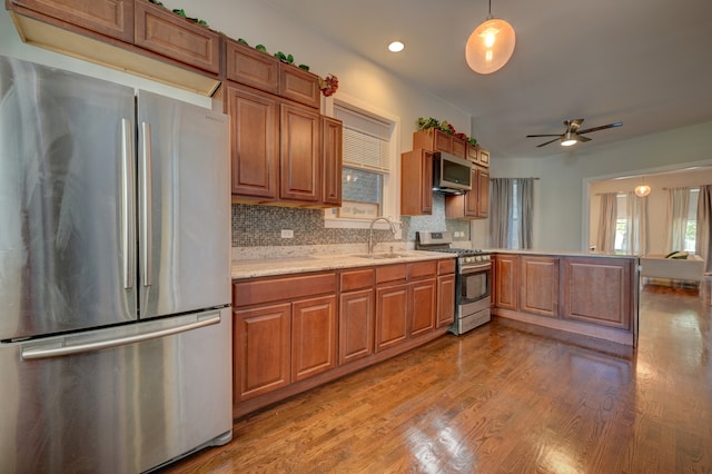 kitchen with pendant lighting, light hardwood / wood-style floors, sink, decorative backsplash, and appliances with stainless steel finishes