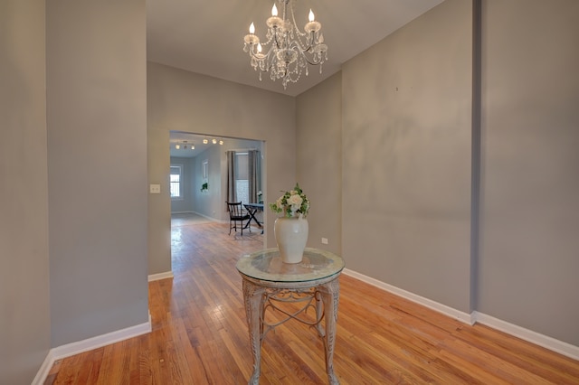 hall with wood-type flooring and a notable chandelier