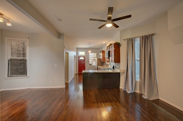 interior space with ceiling fan, dark wood-type flooring, stainless steel fridge, and kitchen peninsula