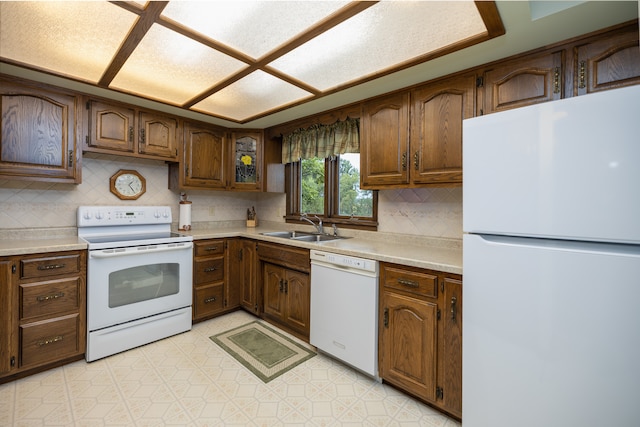 kitchen featuring white appliances, decorative backsplash, and sink