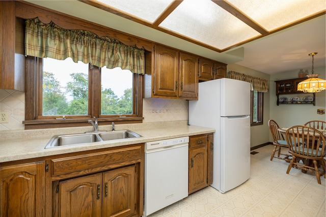 kitchen with decorative light fixtures, tasteful backsplash, sink, and white appliances