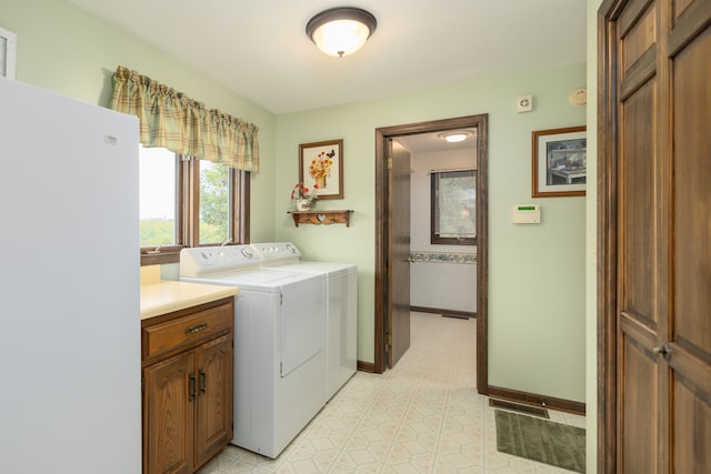 clothes washing area featuring independent washer and dryer, light tile patterned floors, and cabinets