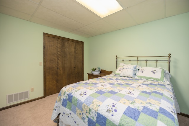 carpeted bedroom featuring a closet and a paneled ceiling