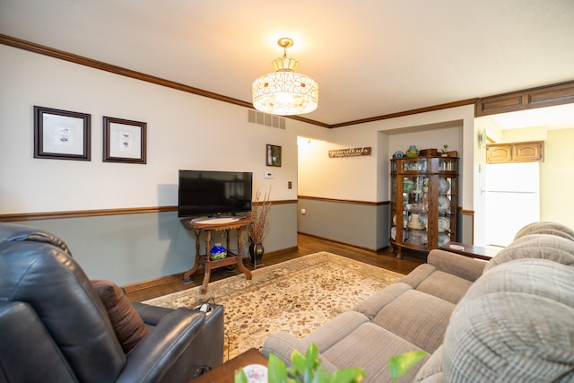 living room featuring an inviting chandelier, crown molding, and hardwood / wood-style floors