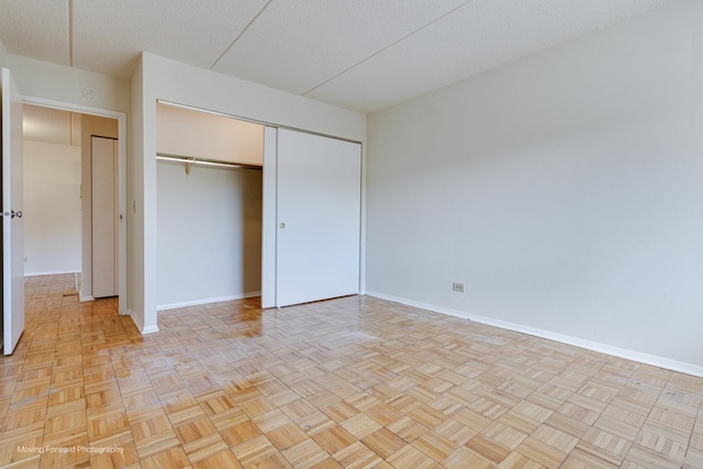 unfurnished bedroom with a textured ceiling, a closet, and light parquet flooring