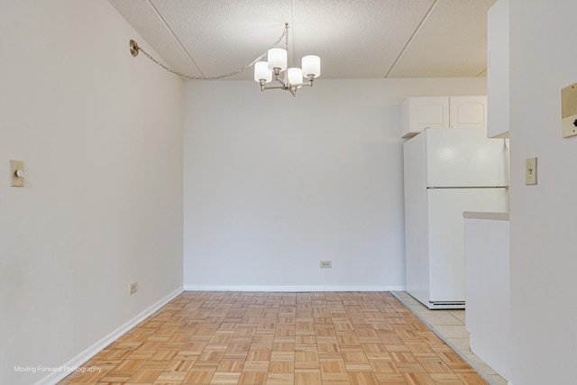 unfurnished dining area featuring light parquet flooring, a notable chandelier, and a textured ceiling