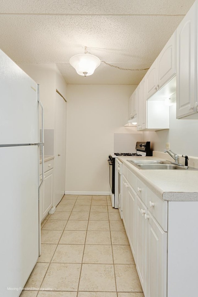 kitchen featuring sink, white cabinetry, white refrigerator, light tile patterned flooring, and range with gas cooktop