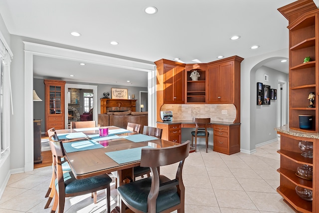 dining space featuring a fireplace, built in desk, and light tile patterned floors