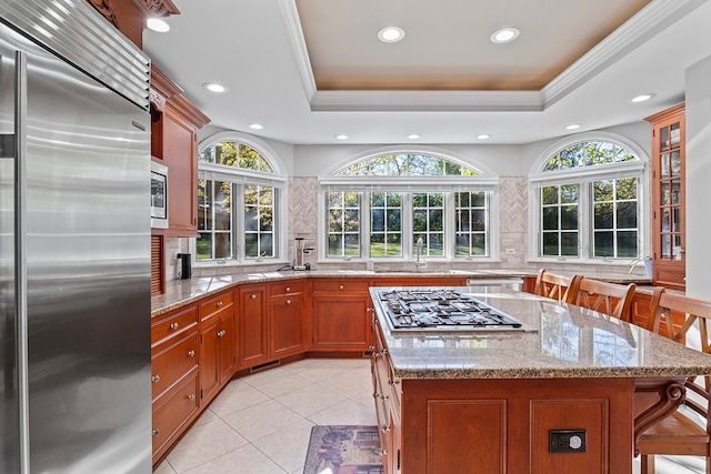 kitchen featuring built in appliances, a kitchen breakfast bar, a tray ceiling, and a kitchen island