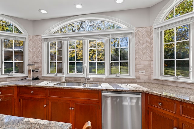 kitchen featuring decorative backsplash, stainless steel dishwasher, sink, and light stone counters