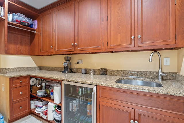 kitchen featuring light stone countertops, wine cooler, and sink