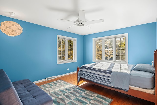 bedroom with ceiling fan, hardwood / wood-style flooring, and multiple windows