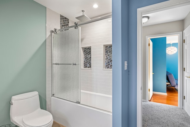 bathroom with combined bath / shower with glass door and toilet