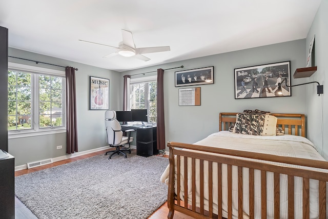 bedroom with multiple windows, wood-type flooring, and ceiling fan