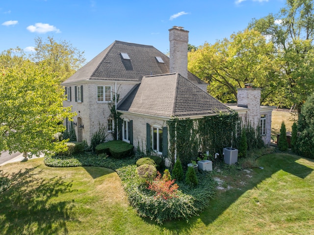 rear view of house featuring a lawn and central AC unit