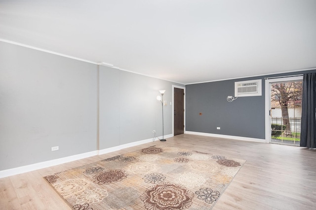 empty room featuring a wall mounted air conditioner, hardwood / wood-style flooring, and ornamental molding