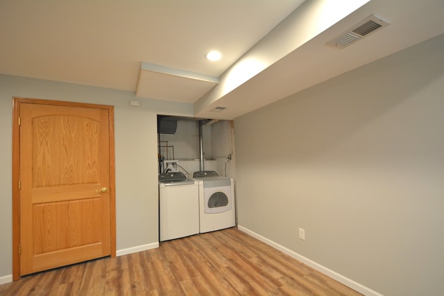 clothes washing area featuring light hardwood / wood-style flooring and washer and clothes dryer