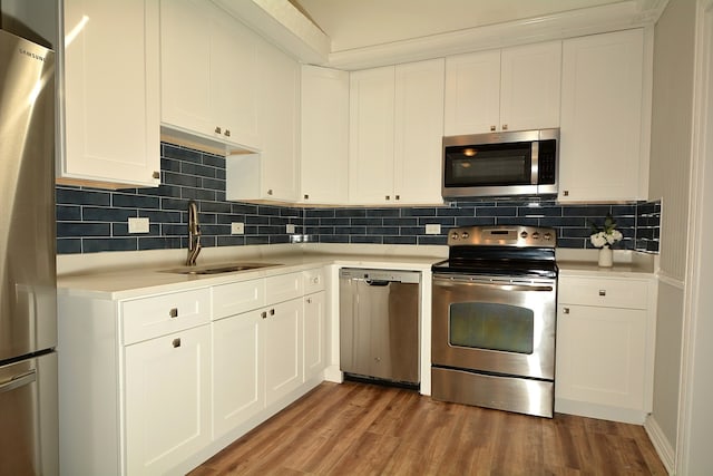 kitchen with stainless steel appliances, white cabinets, and hardwood / wood-style flooring