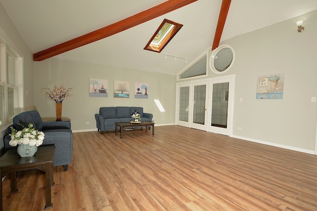 living room featuring beamed ceiling, light hardwood / wood-style flooring, a skylight, and high vaulted ceiling