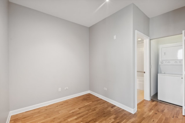 spare room featuring light hardwood / wood-style floors and stacked washing maching and dryer