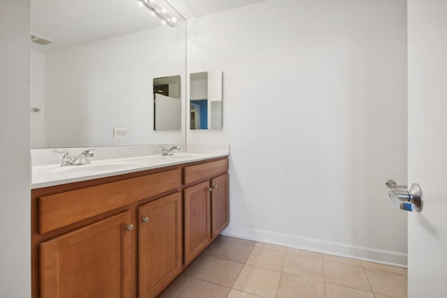 full bath with double vanity, tile patterned flooring, a sink, and baseboards